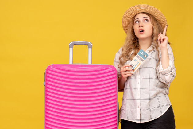 靠近情绪激动的年轻女士戴着帽子 出示车票 站在她粉红色的包旁边 指着上面漂亮购物者指向