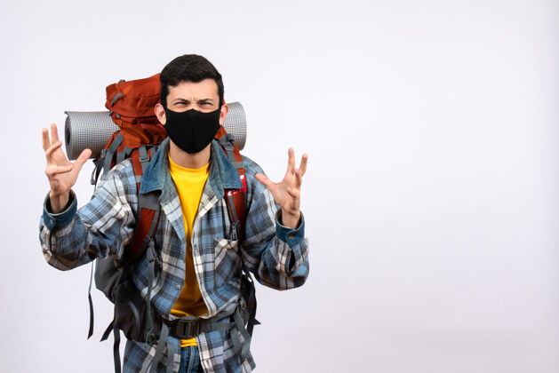 成人正面图愤怒的年轻徒步旅行者背着背包和面具举起手轮廓肖像脸