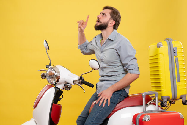 微笑旅游概念与年轻的重点胡须男子坐在摩托车上 并期待着它的黄色向上成人摩托车