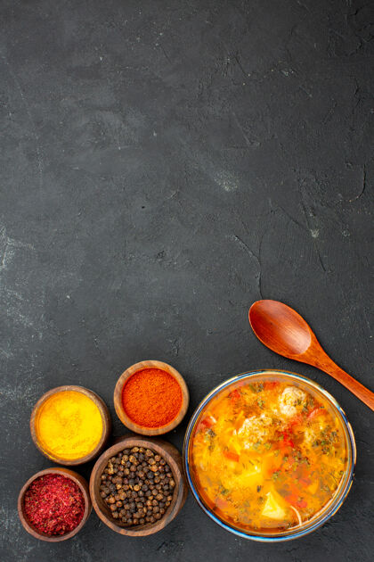 不同顶视图美味的汤与不同的调味料对灰色背景的汤餐食品肉类调味料辛辣新鲜美味勺子