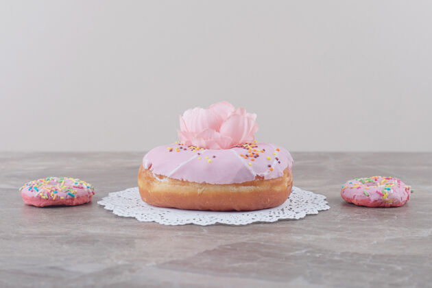 鲜花小甜甜圈旁边的一个大甜甜圈上装饰着一朵花大理石甜点美味糕点