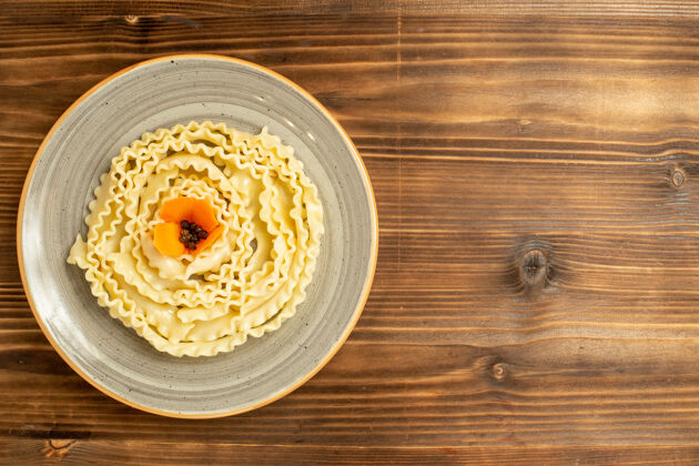 盘子顶视图生面团在棕色桌子上的盘子里形成生面团生面团美味烘焙食品生的