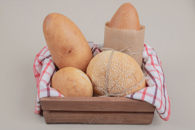 美味用桌布把新鲜的面包糕点放在木篮里小麦木头美味