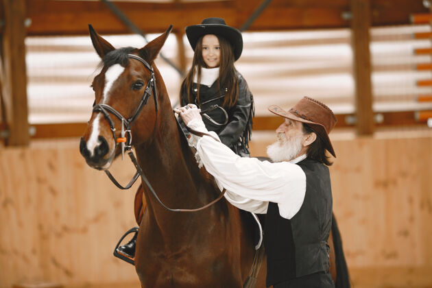 种马戴头盔的女孩学骑马教练教小女孩老年人女孩人