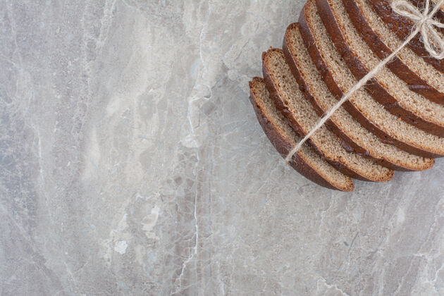 美味用绳子把棕色面包片放在大理石表面烘焙健康面包
