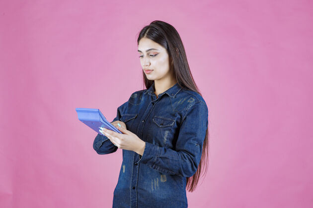 现金年轻的女人手里拿着一个蓝色的计算器在计算年轻人会计女性