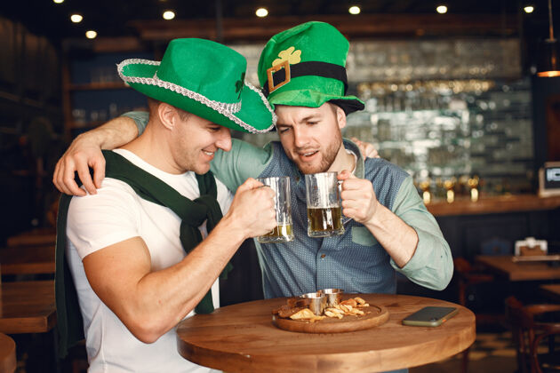 帽子戴绿帽子的男人朋友们庆祝圣帕特里克节在酒吧庆祝啤酒年轻绿帽子