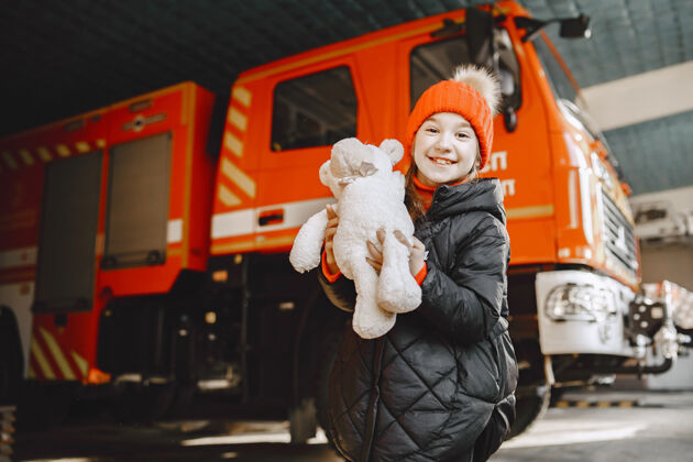 可爱消防站的孩子拿着玩具的女孩消防车附近的孩子害怕帮助小