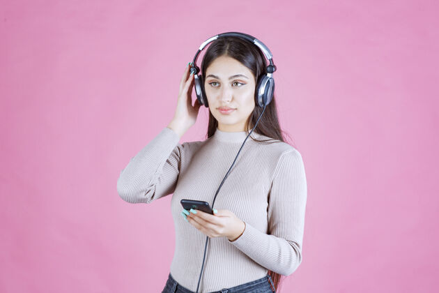 女人戴着耳机在智能手机前放音乐的年轻女人成人聪明旋律