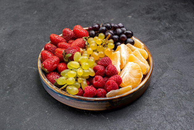 水果前视图水果成分草莓葡萄覆盆子和橘子托盘内黑暗的空间食品甜点生的