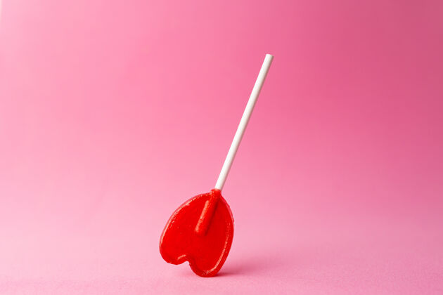美味一个单一的心形棒棒糖在粉红色背景特写镜头糖果心美味