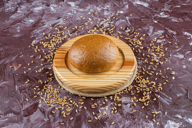 小麦一个木制盘子 上面放着新鲜的棕色面包和种子 背景很浅面包顶视图桌子