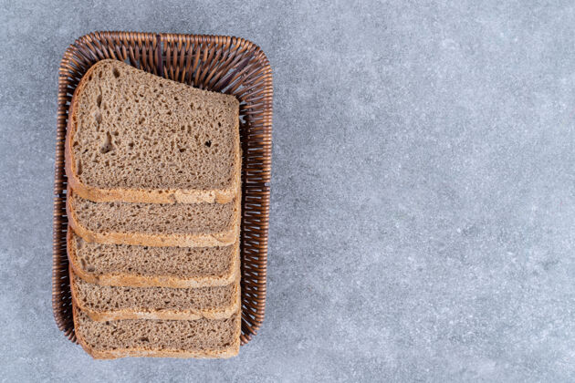 面包皮石桌上放着柳条筐的黑面包片面包屑面包脆