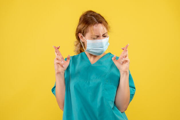 医院黄墙上年轻女医生穿着医疗服 戴着口罩的正面图支持成人面部