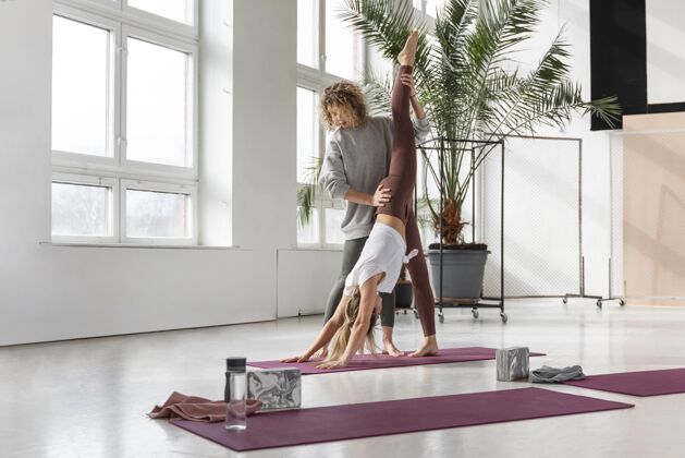 运动全镜头瑜伽老师帮助女人健身室内瑜伽