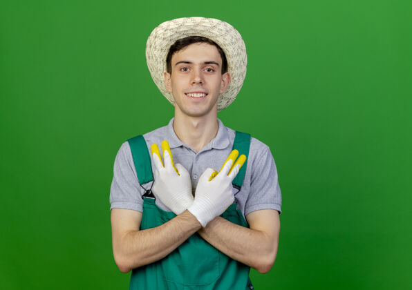 佩戴微笑的年轻男园丁戴着园艺帽和手套手势胜利手势手套帽子复制