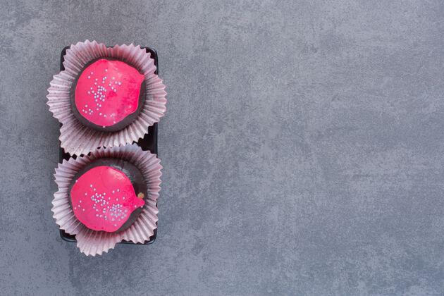 糕点黑盘子上有粉红釉的巧克力球球糖果背景