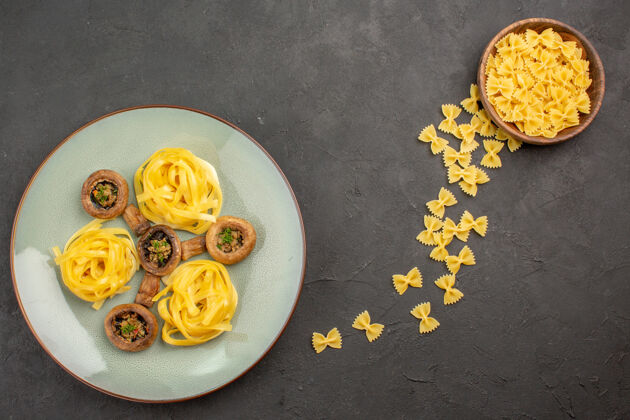 成熟顶视图煮熟的蘑菇和意大利面在一张深色的桌子上蘑菇成熟的野生一餐烘焙食品深色美食