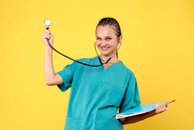 球拍女医生穿着医用套装 手持听诊器 黄色墙壁上的分析听诊器护士女医生