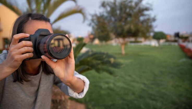 光学女孩在户外用专业单反相机拍了一张自然特写的照片镜头旅游摄影师