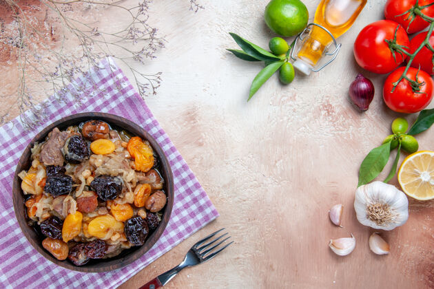 大蒜顶部特写镜头：带干果的肉饭在桌布上西红柿大蒜油柠檬叉食物水果饮食