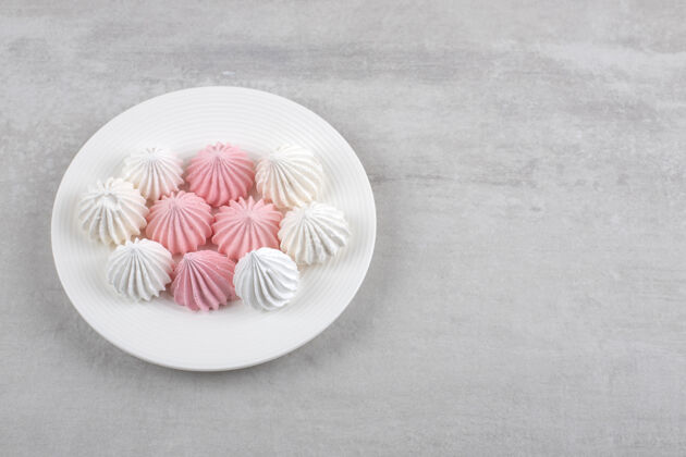 甜点粉色和白色的蛋白酥皮放在盘子里 放在大理石桌上蛋白酥皮卡路里盘子
