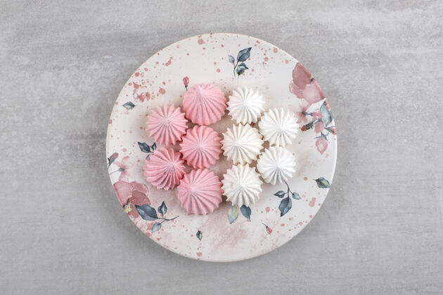 新鲜石头桌上摆着一盘白色和粉色的酥皮糖茶碟食品糕点