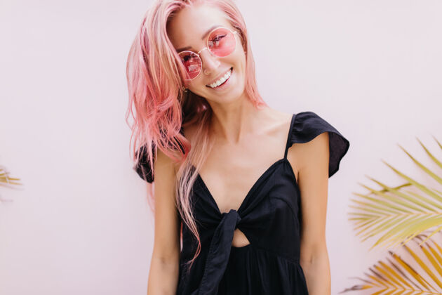 表情一个长着粉红色头发的女人站在工作室里奇异的棕榈树旁微笑女性浪漫