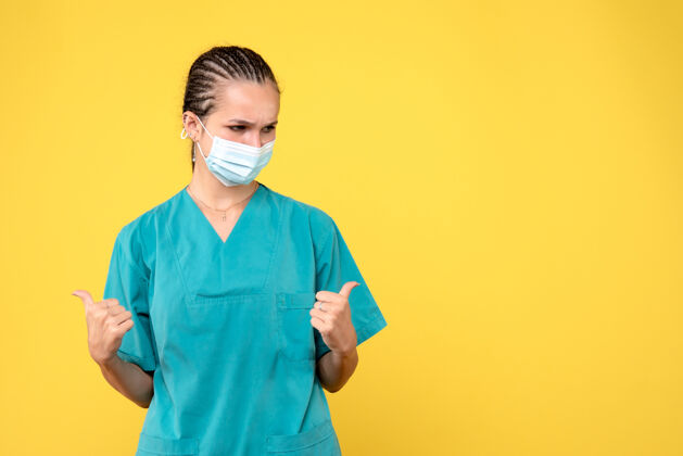 健康黄墙上穿着医疗服 戴着无菌口罩的女医生的正面图面具人病毒
