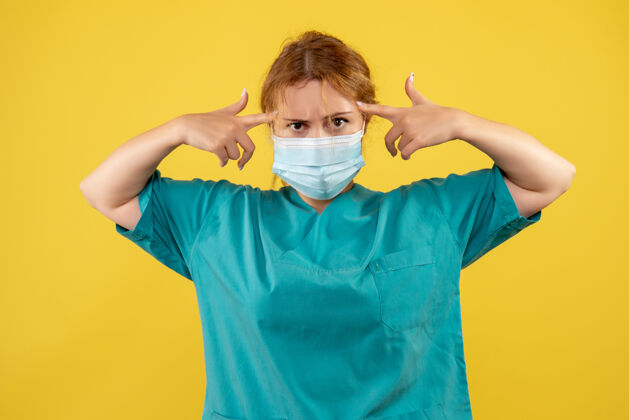 面具黄墙上年轻女医生穿着医疗服 戴着口罩的正面图人正面医疗