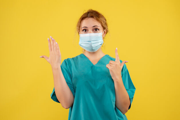 西装黄墙上年轻女医生穿着医疗服 戴着口罩的正面图脸医院人