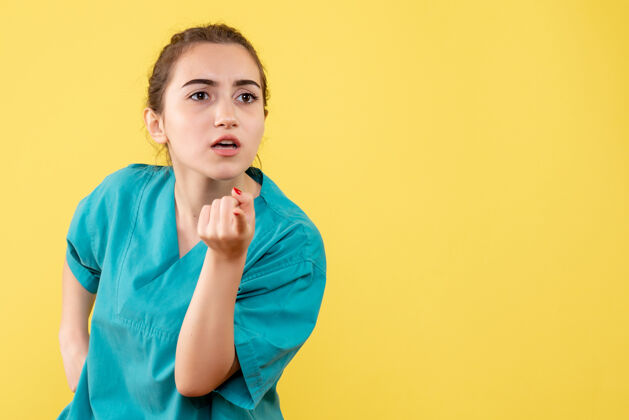 快乐黄墙上年轻女医生穿着医用衬衫的正面图成人正面护士