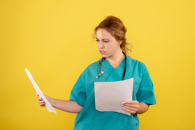 快乐黄色墙壁上穿着医疗服的女医生手持分析的正面图人护士女医生