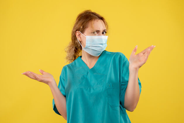 人黄色墙壁上戴着无菌防护面具的女医生的正视图肖像成人医院