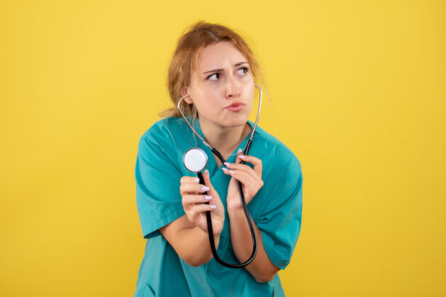 仪器黄色墙上穿着带听诊器的医用衬衫的女医生的正视图衬衫护士前面