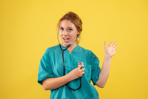 护士黄色墙壁上穿着带听诊器的医疗服的女医生的正视图情绪前台仪器