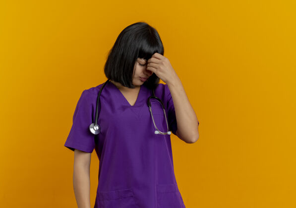 手失望的年轻黑发女医生穿着制服用听诊器把手放在额头上听诊器医生深色