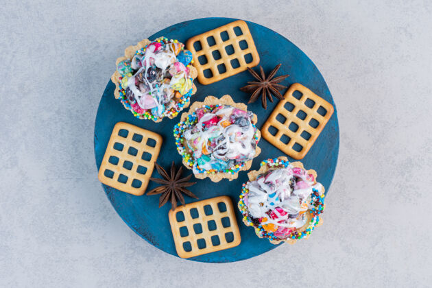 糕点饼干和糖果蛋糕放在大理石桌上的一块板上美味纸杯蛋糕糖果