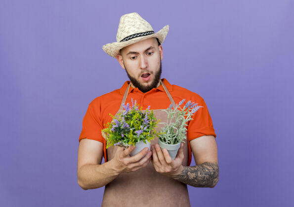 复制震惊的男园丁戴着园艺帽子拿着花盆看穿男花园