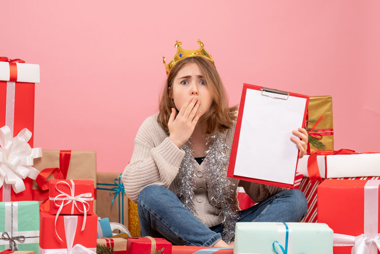 笔记本电脑正面图年轻女性围坐在礼物旁边 手里拿着纸条年礼物粉色