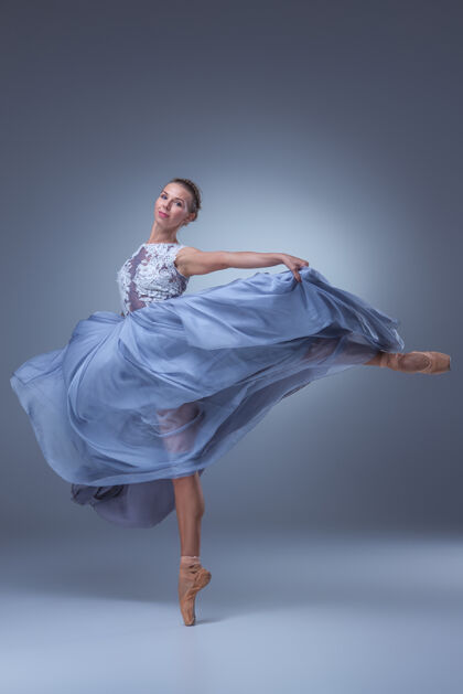 成人美丽的芭蕾舞演员在蓝色背景上穿着蓝色长裙跳舞平衡戏剧服装