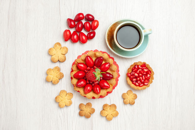 水果俯瞰白色桌子上的小蛋糕 水果饼干和一杯茶小蛋糕小吃草莓