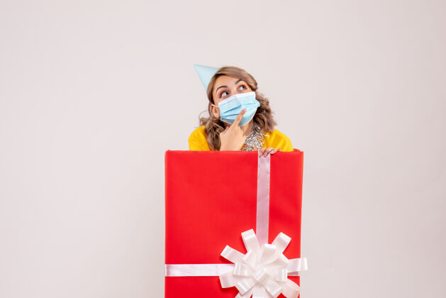 可爱正面图：戴着面具的红色礼品盒里的年轻女性情感购物者病毒