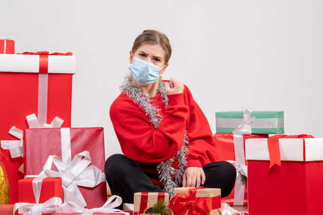 面具正面图：年轻女性戴着无菌面具坐着 手里拿着圣诞礼物人绝育礼物