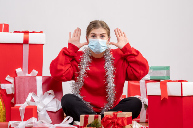 情绪正面图：年轻女性戴着无菌面具坐着 手里拿着圣诞礼物成人礼物病毒