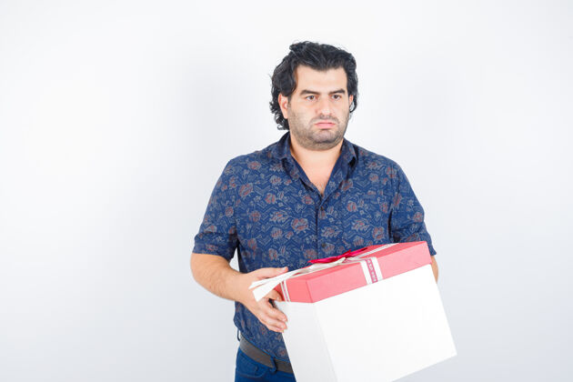 现代成熟的男人拿着礼盒 一边看着衬衫一边若有所思前视图盒子商人退休