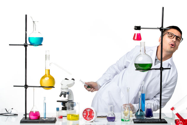 视图正面图：男化学家穿着白色的医疗服 在房间里用白色背景的解决方案 实验室病毒科学冠状病毒大流行溶液内部罐子