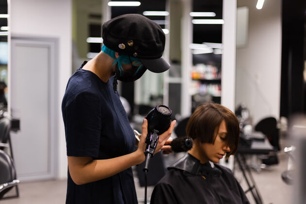 面膜一个专业的女理发师给客户理发这个女孩戴着面具坐在美容院里理发师发型师顾客