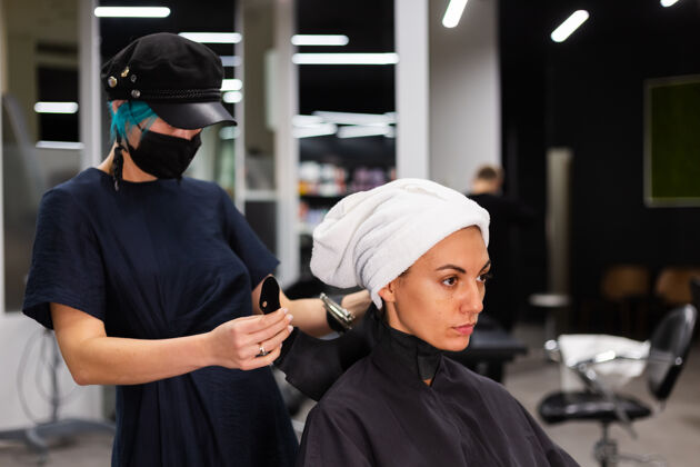 工人一个专业的女理发师给客户理发这个女孩戴着面具坐在美容院里客户理发师爆发