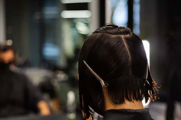 理发师一个专业的女理发师给客户理发这个女孩戴着面具坐在美容院里沙龙设备发廊
